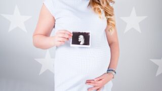 woman wearing white cap sleeved dress holding ultrasound result photo