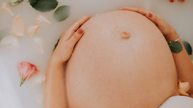 pregnant woman sitting on bathtub