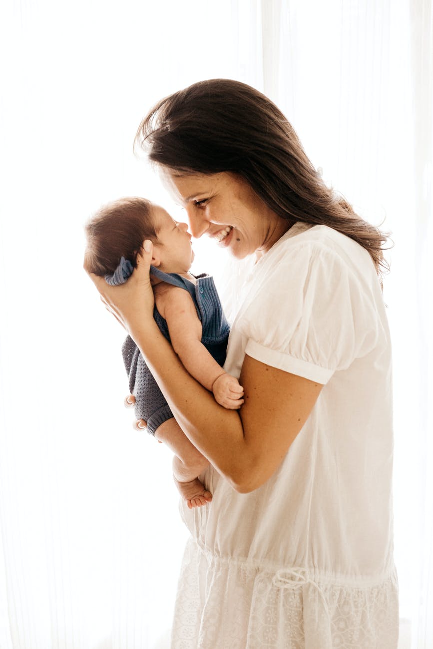 side view photo of smiling woman carrying her baby